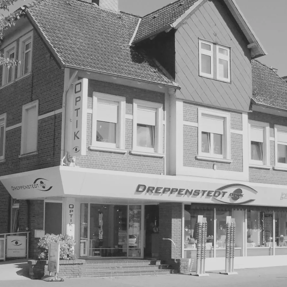 Das Geschäftshaus von Dreppenstedt Optik in Tostedt mit dem Schriftzug über den Schaufenstern, schwarzweiß fotografiert