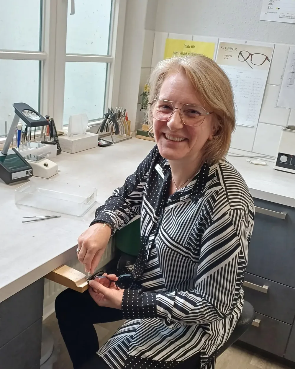 Eine Augenoptikerin an ihrem Arbeitsplatz in der Werkstatt